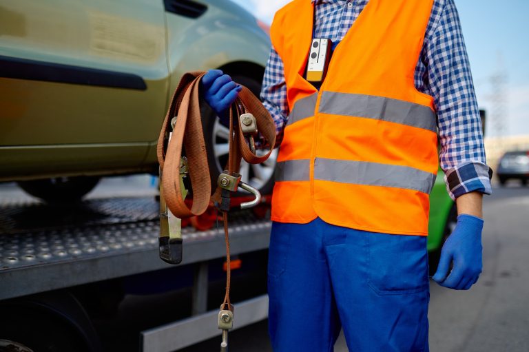 Male tow truck assistant holding fastening belts