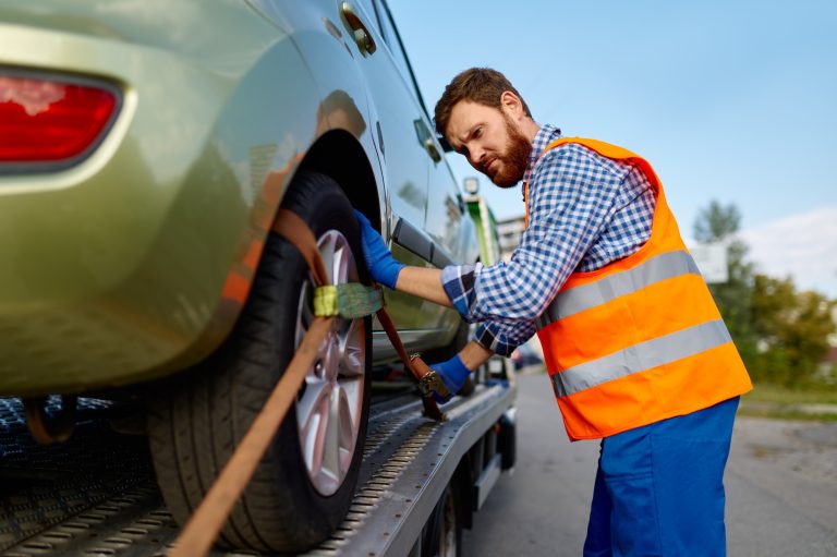 Tow truck operator fixing car on platform