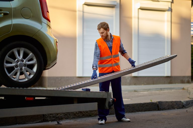 Worker preparing tow truck platform for car